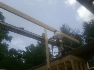 Carpenter setting a ridge beam over a new addition frame — Ice Dam Removal by Roofing Brothers in Yutan