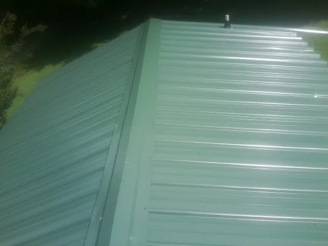 New green metal panels meeting at the ridge of a roof — Flat Roof Repair work by our crew in Yutan