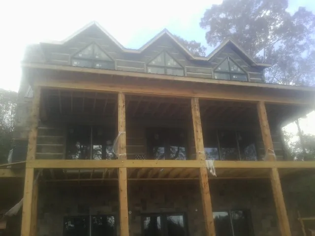 Dormers and porch framing on a large log home under construction — Roof Coating work by our crew in Yutan