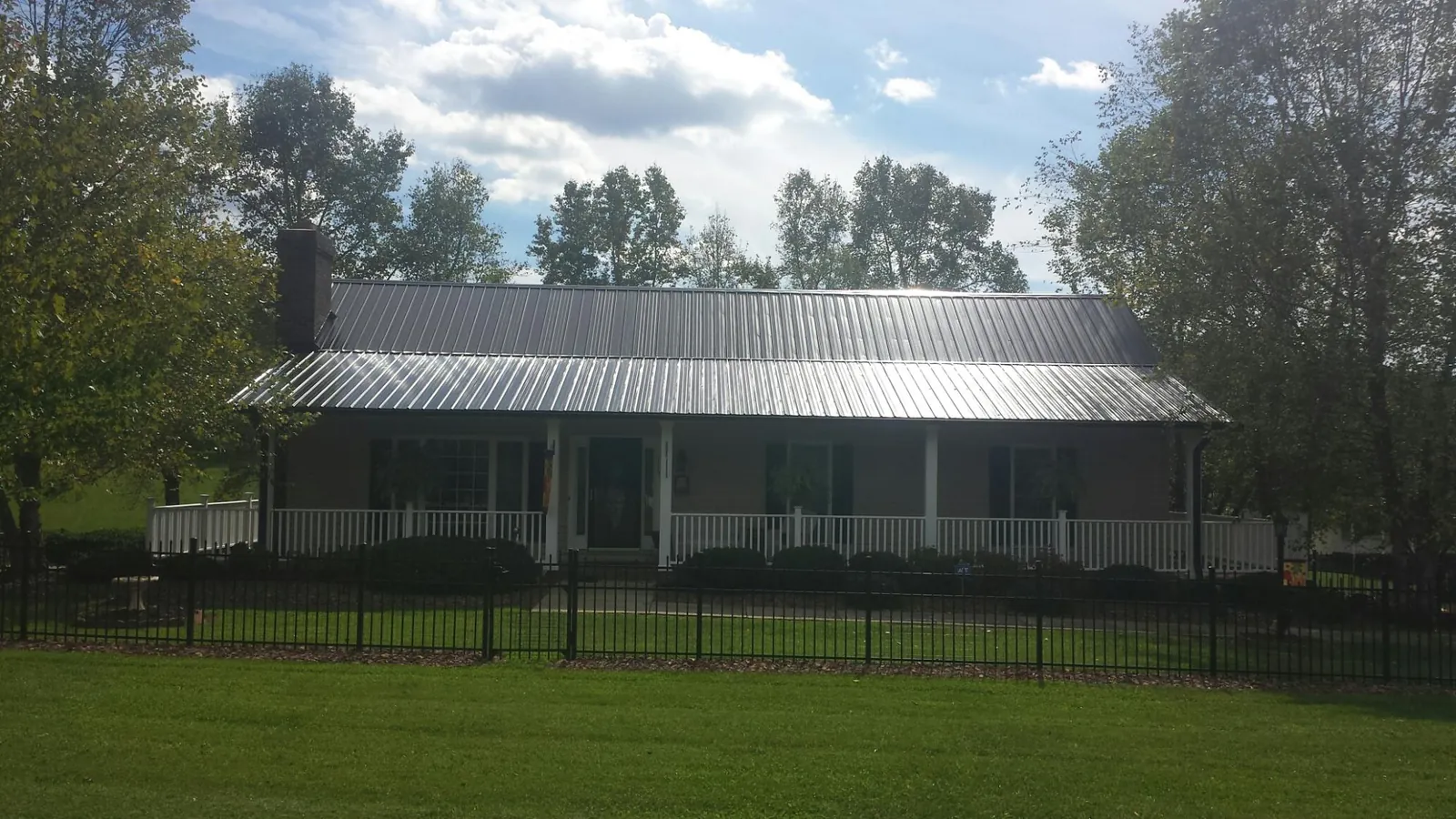 Gray metal roof on a brick ranch with a full width front porch — Gutter Guard Installation work by our crew in Yutan