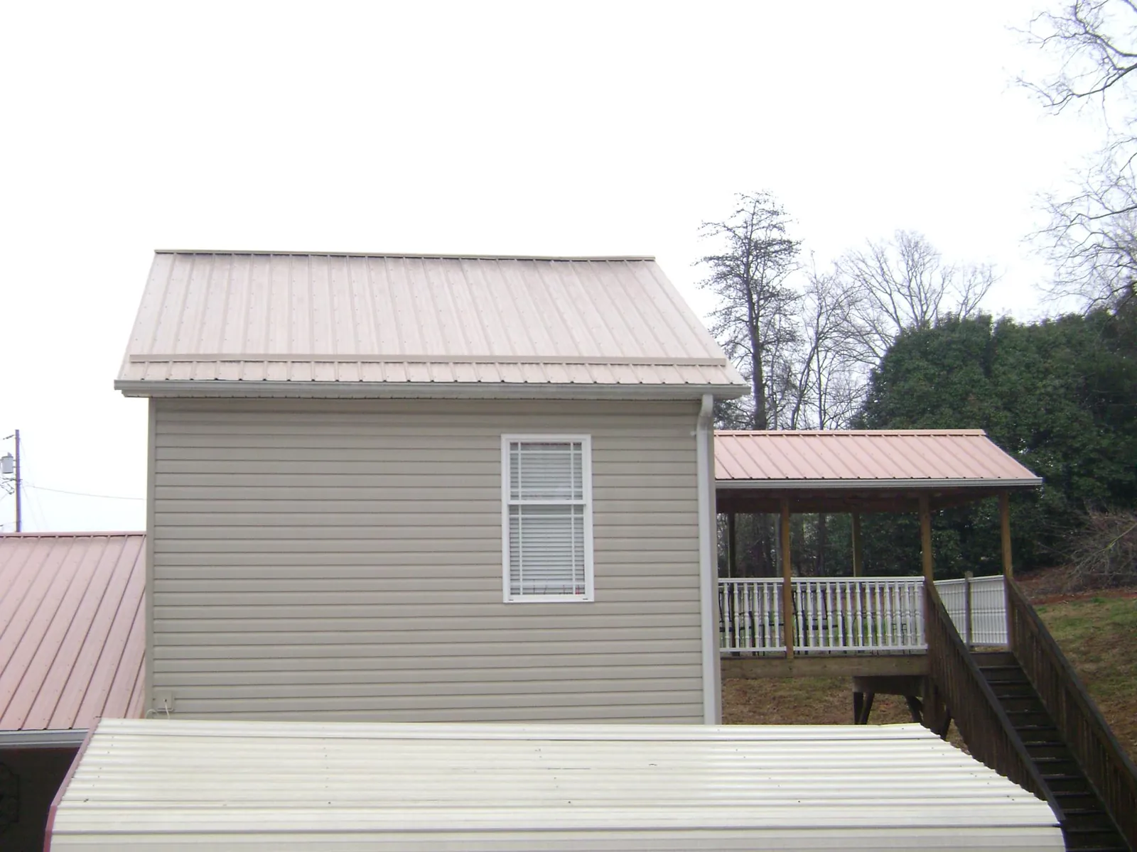 Tan metal roofs on a two story addition and attached porch, from a Roof Replacement job in Yutan