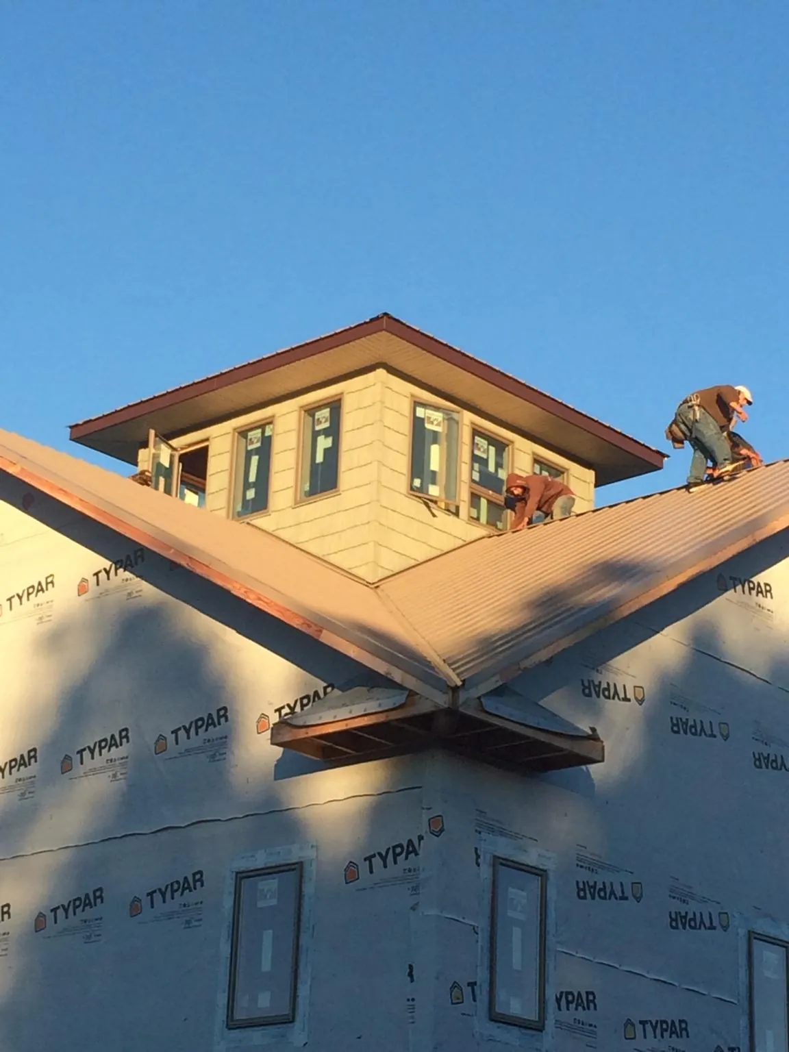 Roofers working around a rooftop cupola on a new metal roof at sunset — Roof Waterproofing in Yutan by Roofing Brothers